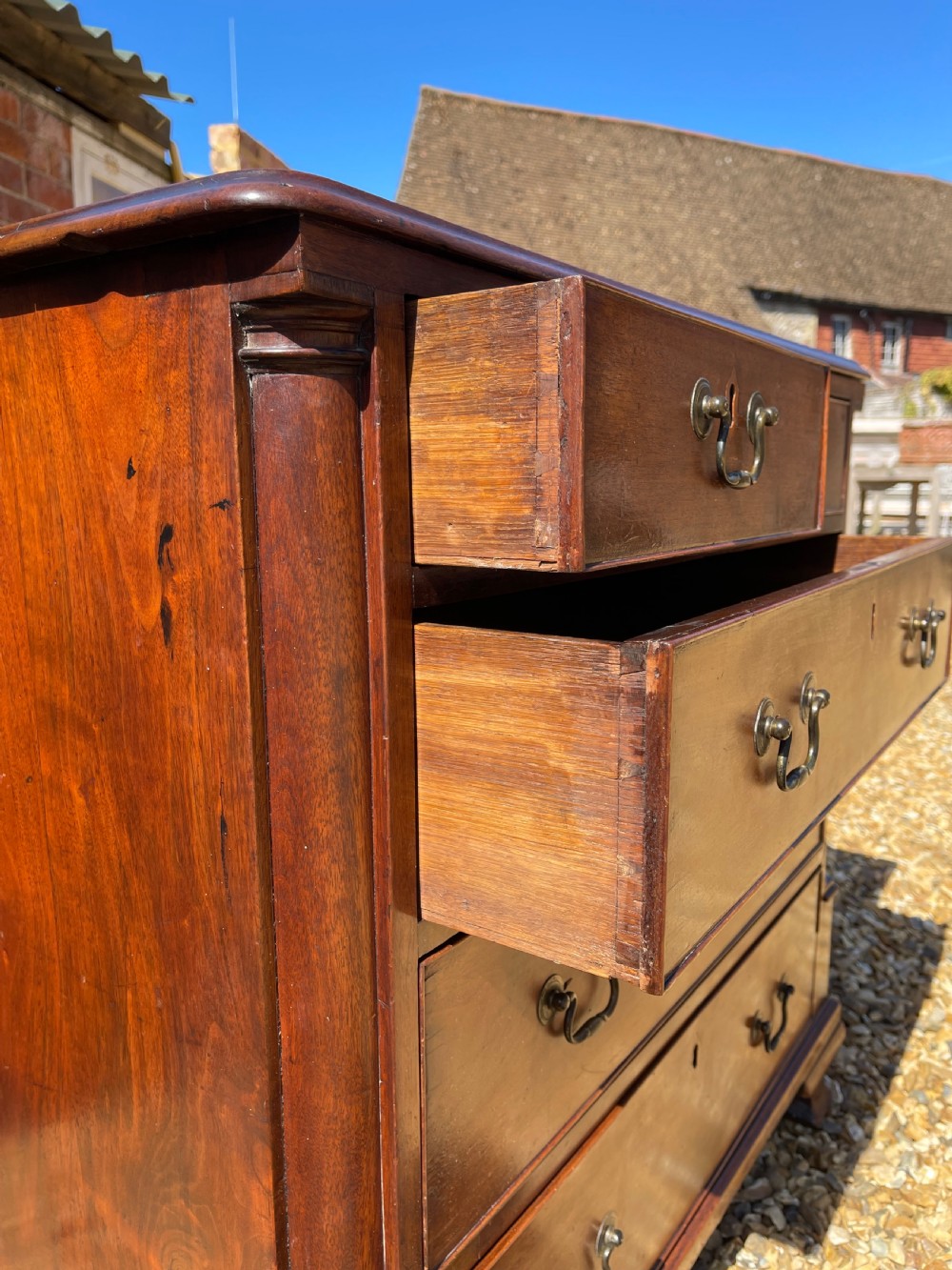 An eighteenth-century Georgian mahogany chest of drawers featuring two short drawers over three long drawers, finished with brass swan-neck handles and bracket feet. View VII