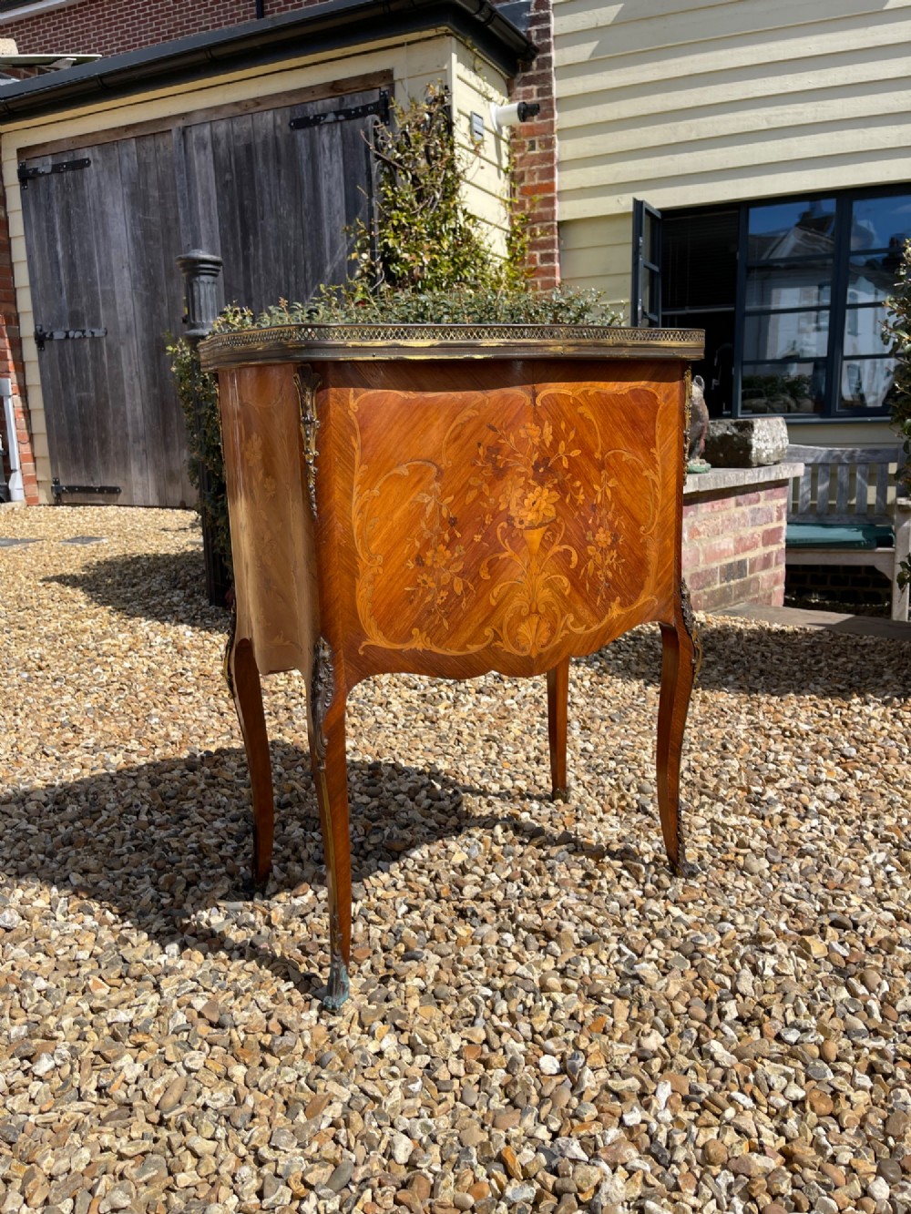 A late nineteenth-century French style side cabinet featuring floral marquetry wood inlay, a variegated marble top surrounded by a pierced brass gallery rim, cabriole legs, and a glazed door. View V
