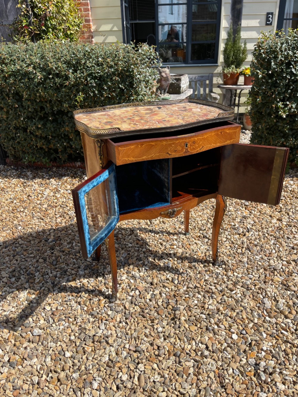 A late nineteenth-century French style side cabinet featuring floral marquetry wood inlay, a variegated marble top surrounded by a pierced brass gallery rim, cabriole legs, and a glazed door. View VI