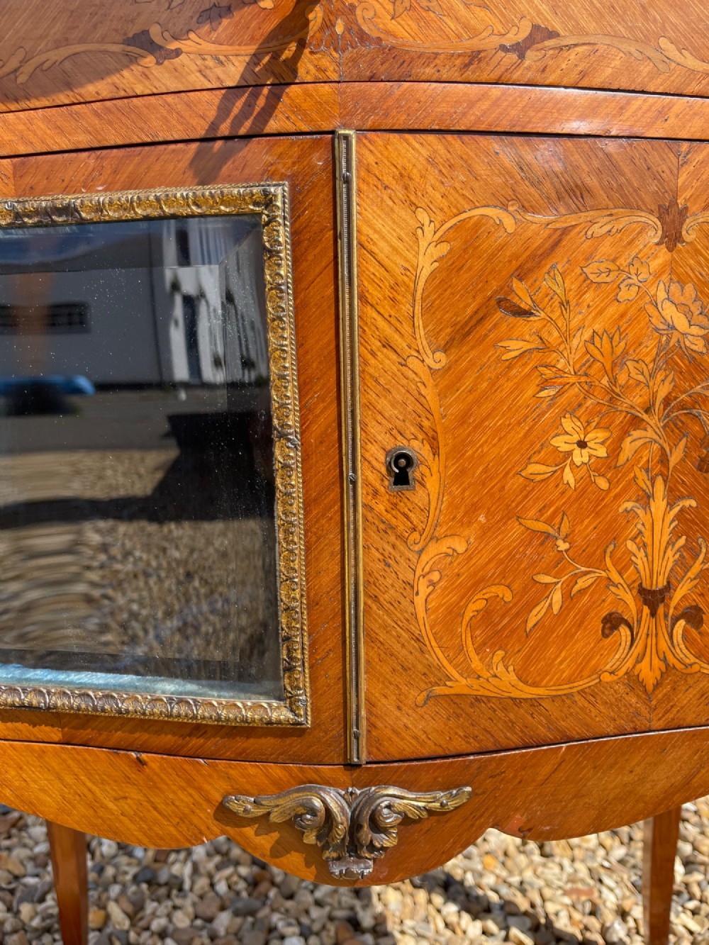 A late nineteenth-century French style side cabinet featuring floral marquetry wood inlay, a variegated marble top surrounded by a pierced brass gallery rim, cabriole legs, and a glazed door. View VII