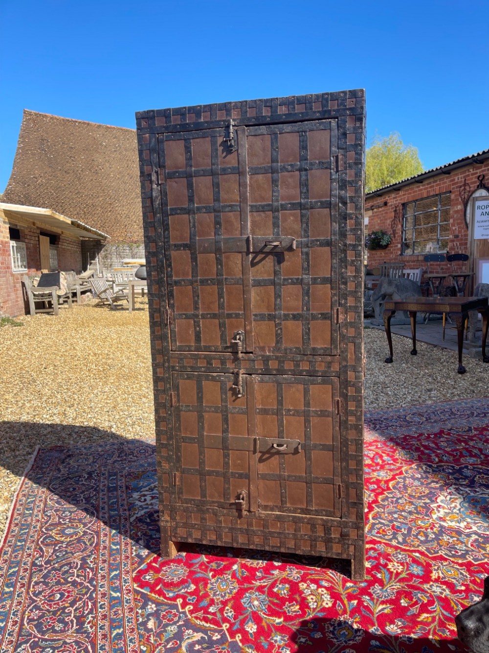 A tall nineteenth-century Indian wooden cupboard bound in dark iron lattice strapping with metal latches and double doors.