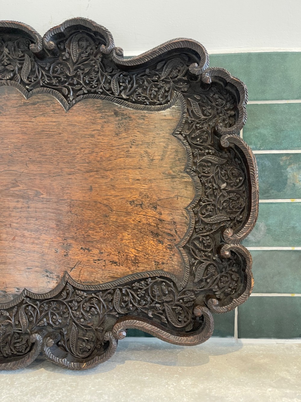 A dark brown carved walnut tray featuring a smooth central panel surrounded by a scalloped, intricately carved floral border. View II
