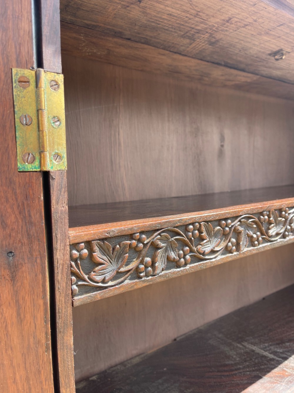 A tall nineteenth-century dark hardwood double-door cupboard decorated with intricate relief foliate carving across the front doors and base. View III