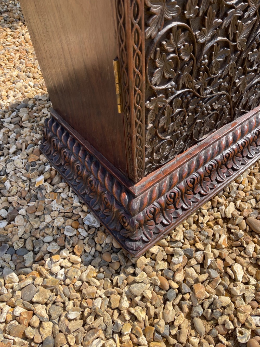 A tall nineteenth-century dark hardwood double-door cupboard decorated with intricate relief foliate carving across the front doors and base. View VII