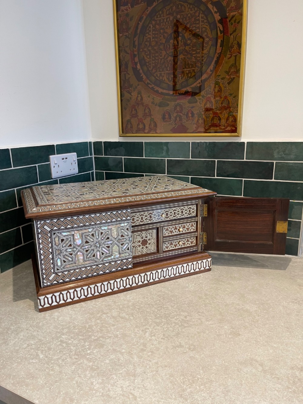An Ottoman wooden tabletop cabinet featuring geometric mother-of-pearl and bone inlay, with a open side door revealing internal drawers.