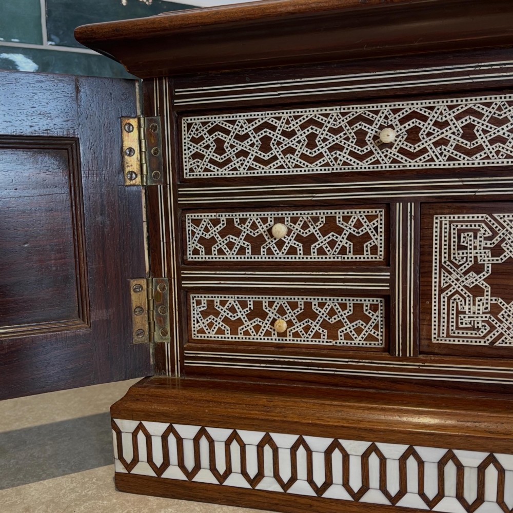 An Ottoman wooden tabletop cabinet featuring geometric mother-of-pearl and bone inlay, with a open side door revealing internal drawers. View III