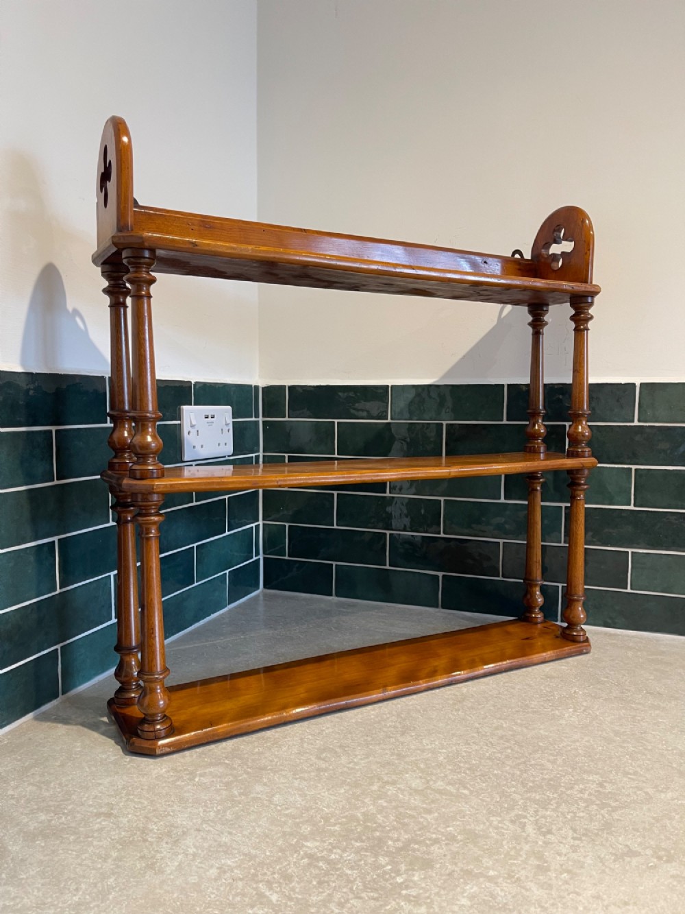 A three-tiered Victorian wall shelf unit made of warm satin birch wood featuring turned column supports and pierced side panels.