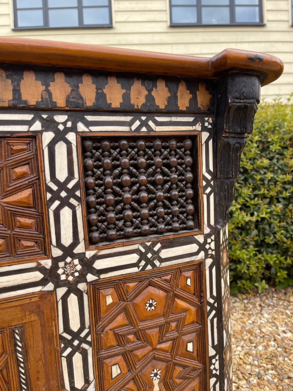 A dark brown rectangular wooden cabinet decorated with geometric bone inlay panels and carved mashrabiya lattice work. View VII