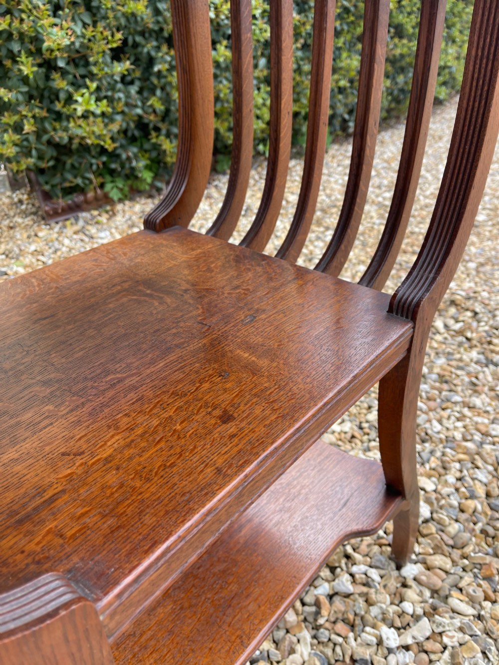 An antique oak side table featuring an inset top panel of six green and terracotta glazed tiles with botanical motifs, raised on curved slatted supports and two lower shelves. View V