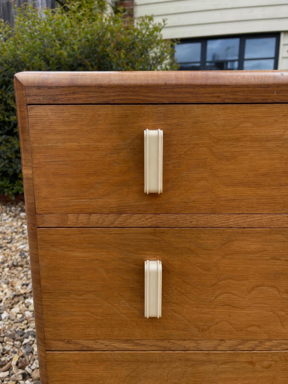 A light golden oak Art Deco chest of drawers featuring three drawers with cream-coloured vertical handles and rounded top edges. View III