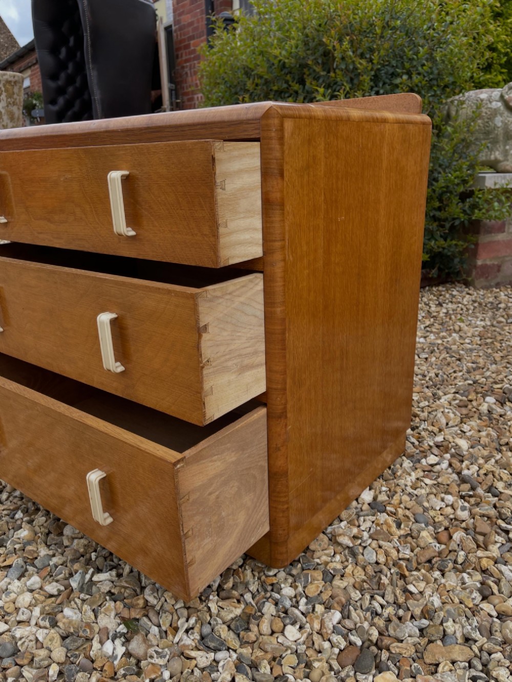 A light golden oak Art Deco chest of drawers featuring three drawers with cream-coloured vertical handles and rounded top edges. View IV