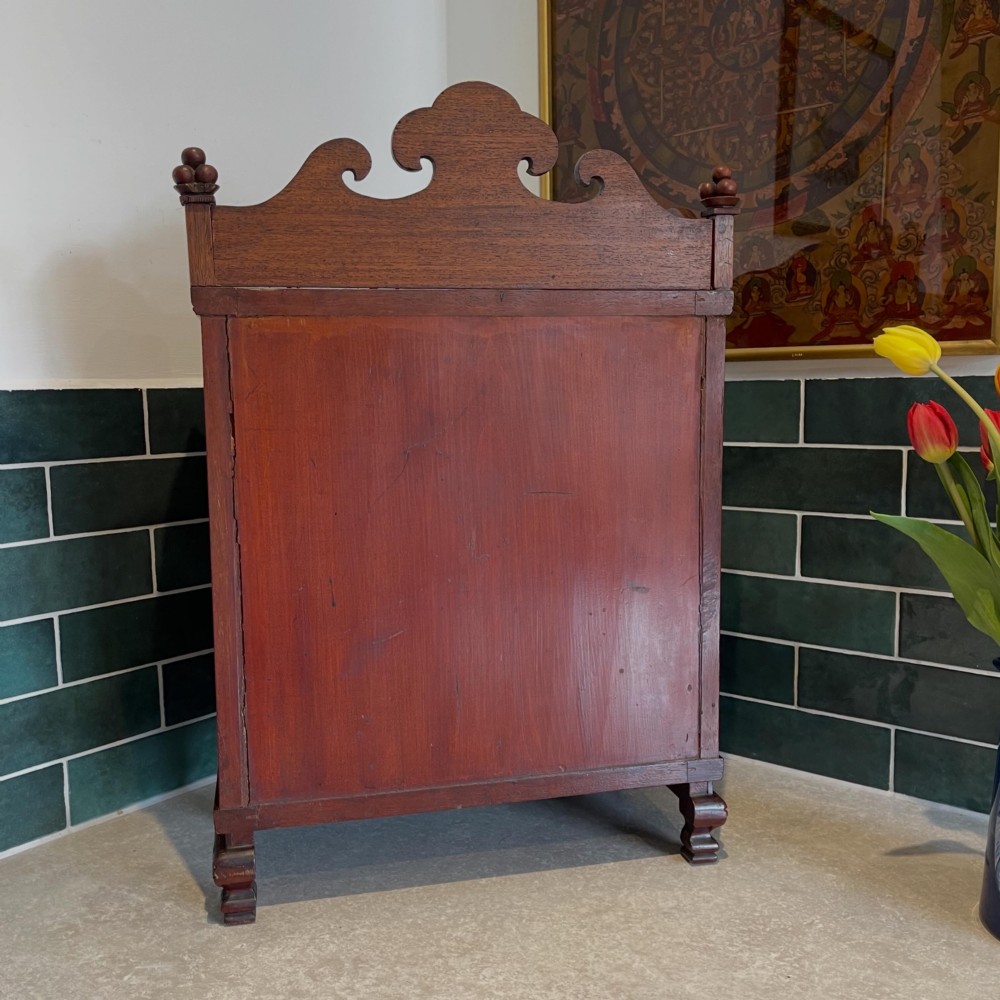 A dark wood Chinese table cabinet featuring two doors embellished with detailed mother-of-pearl landscape inlays, flanked by decorative borders and topped with a carved cresting. View II