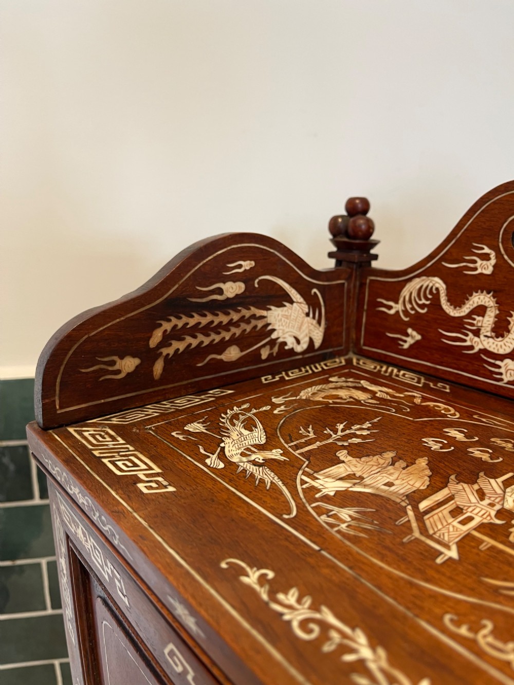 A dark wood Chinese table cabinet featuring two doors embellished with detailed mother-of-pearl landscape inlays, flanked by decorative borders and topped with a carved cresting. View VI