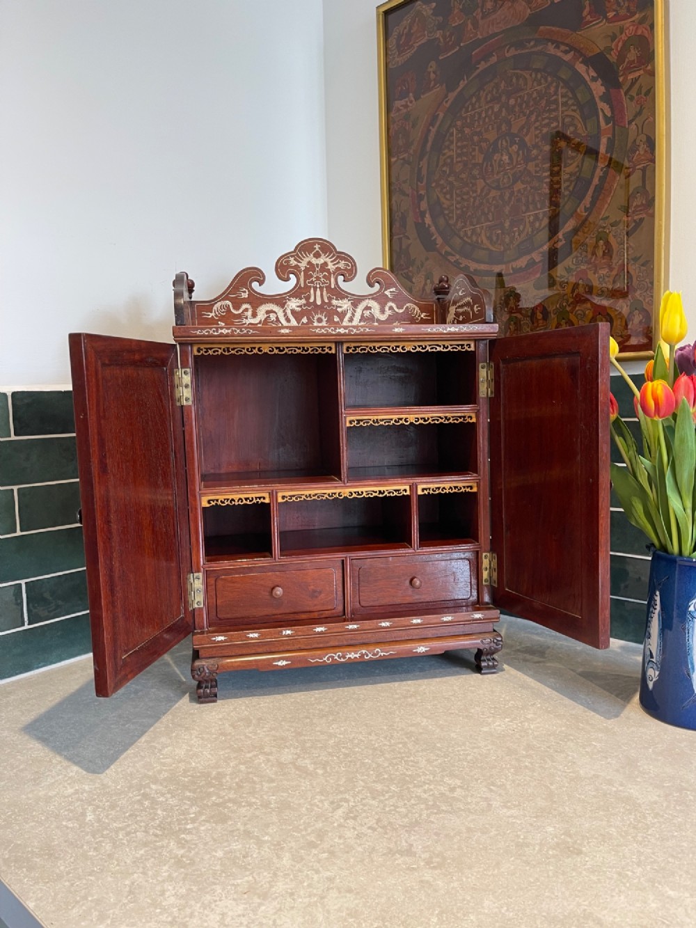 A dark wood Chinese table cabinet featuring two doors embellished with detailed mother-of-pearl landscape inlays, flanked by decorative borders and topped with a carved cresting. View VIII