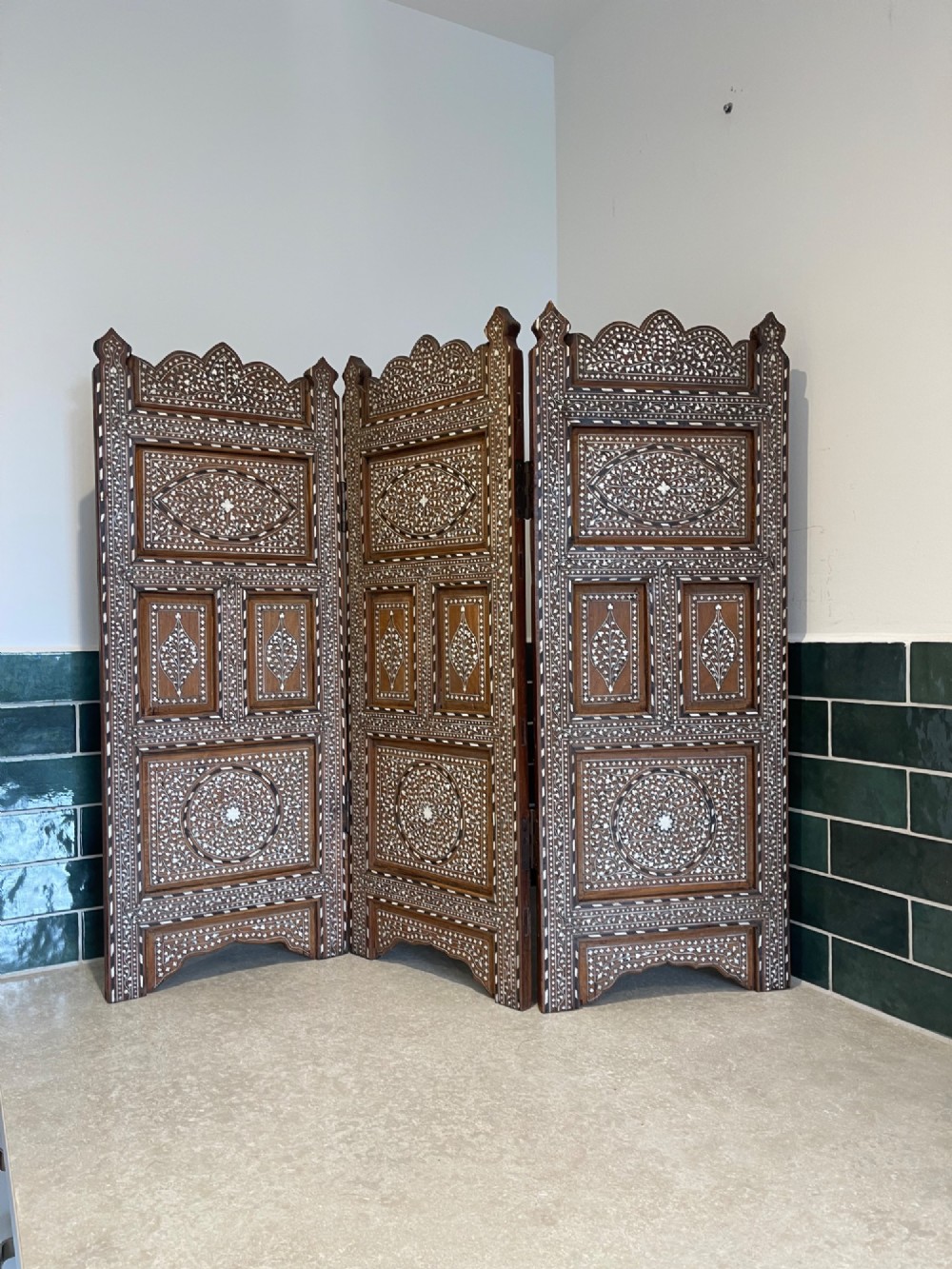 A three-panel Anglo-Indian folding table screen crafted from dark wood with white floral bone inlay patterns.