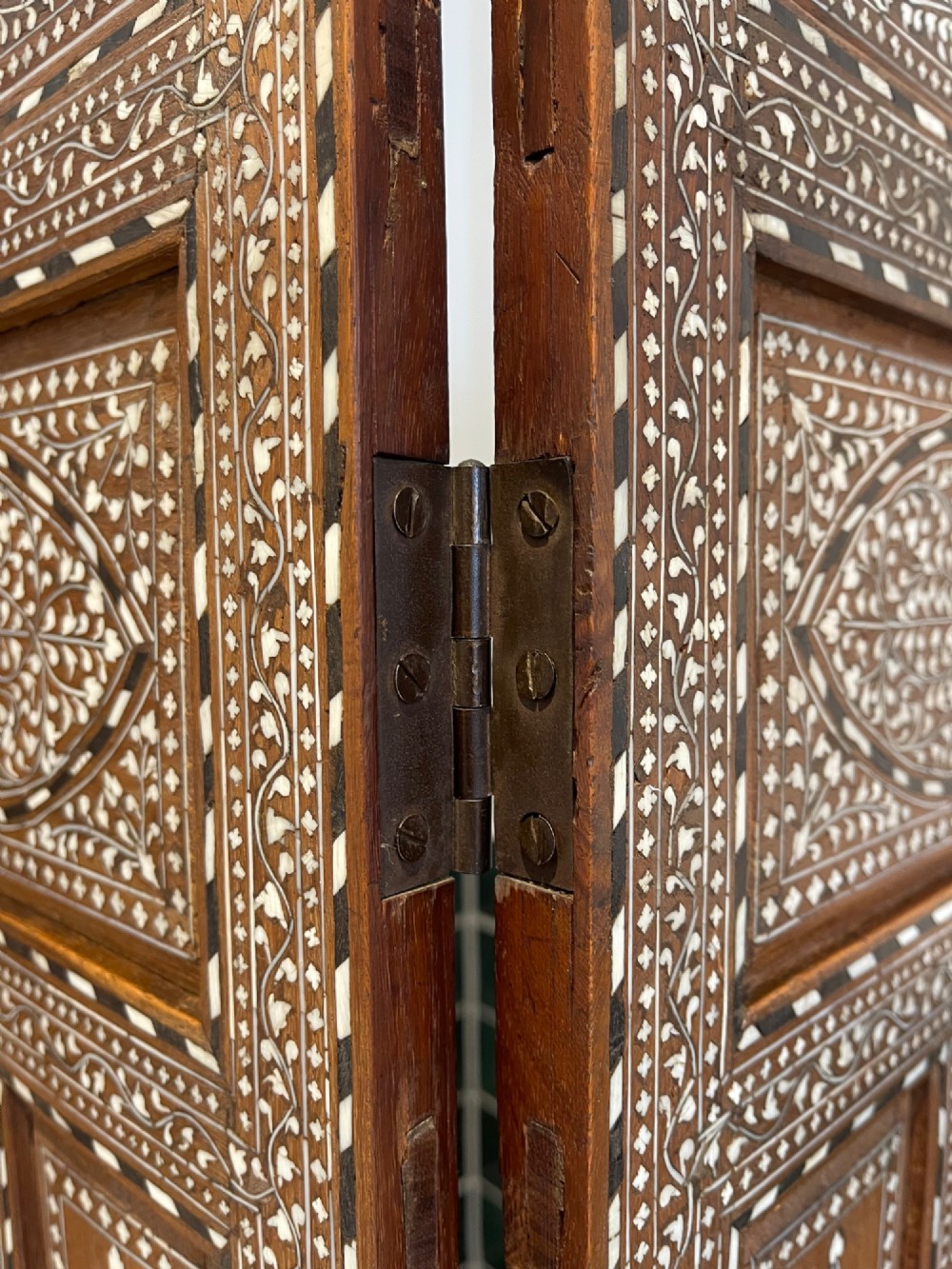 A three-panel Anglo-Indian folding table screen crafted from dark wood with white floral bone inlay patterns. View V