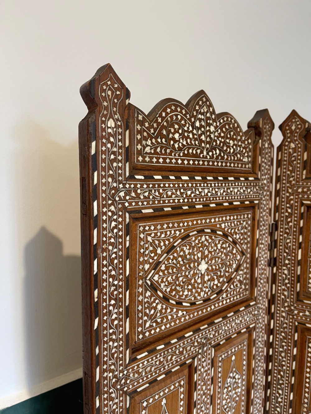 A three-panel Anglo-Indian folding table screen crafted from dark wood with white floral bone inlay patterns. View VI