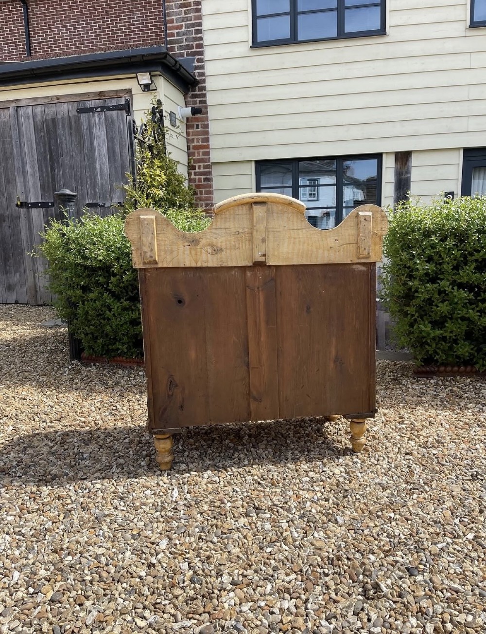 A Victorian painted pine chest of drawers with a carved gallery back, wooden knobs, and turned feet. View II