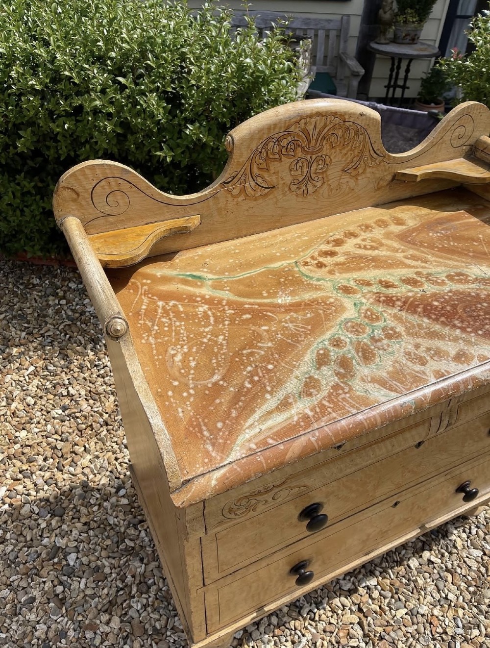 A Victorian painted pine chest of drawers with a carved gallery back, wooden knobs, and turned feet. View V