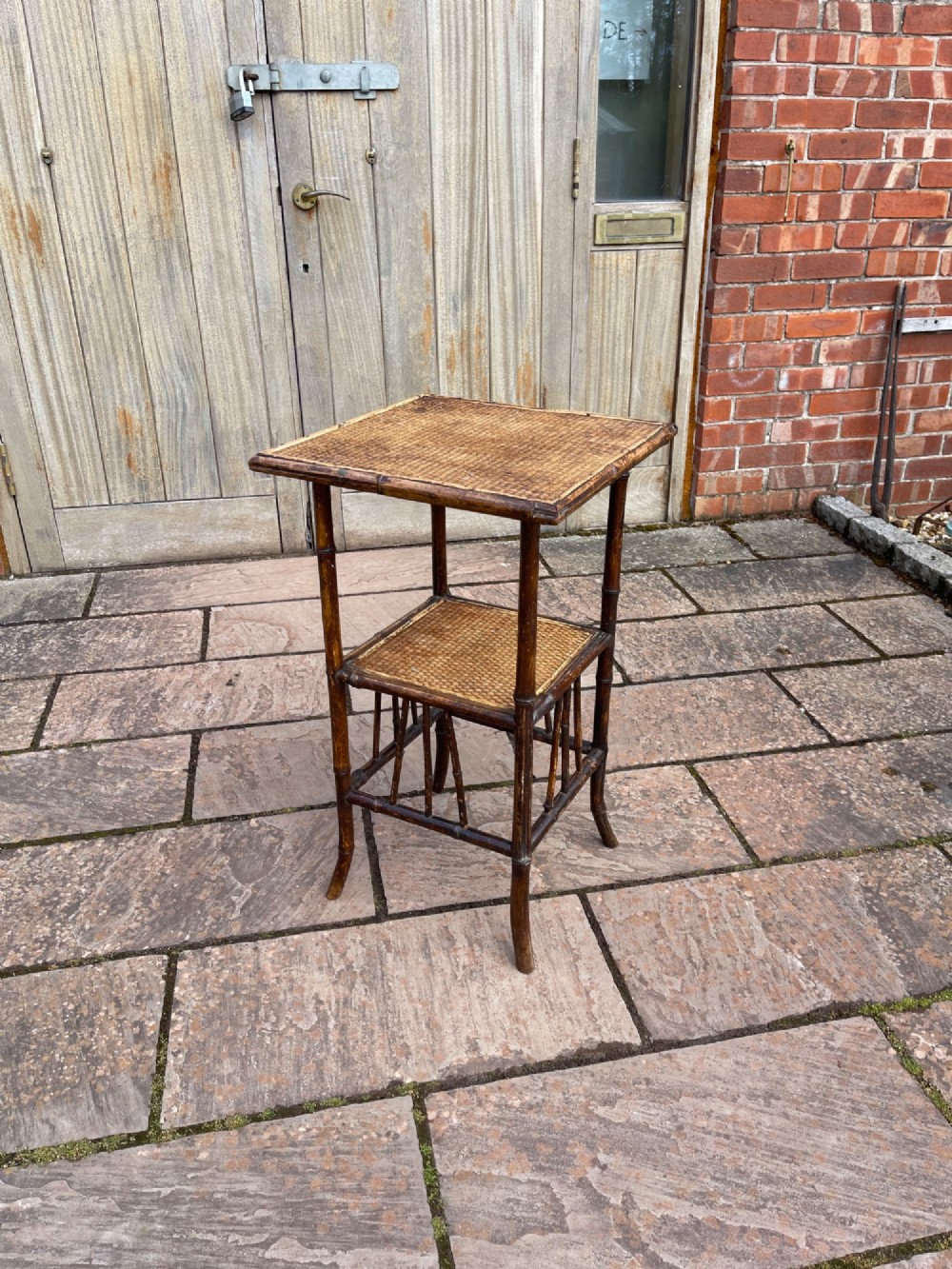 A late Victorian two-tier side table constructed from a dark bamboo frame with woven cane surfaces on the square top and lower shelf.