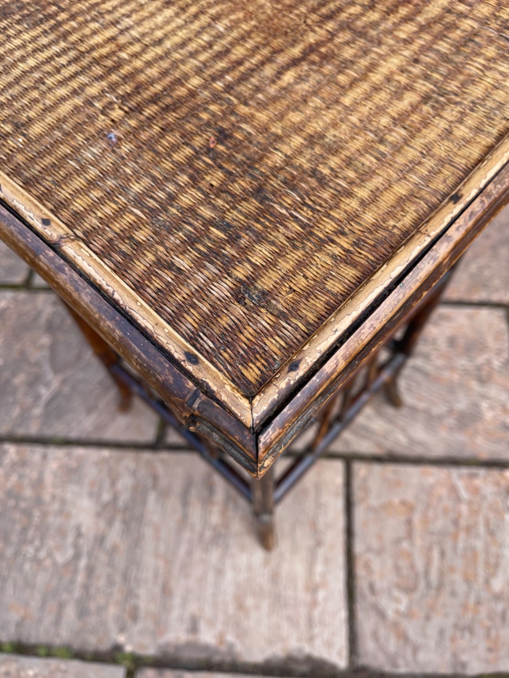 A late Victorian two-tier side table constructed from a dark bamboo frame with woven cane surfaces on the square top and lower shelf. View II