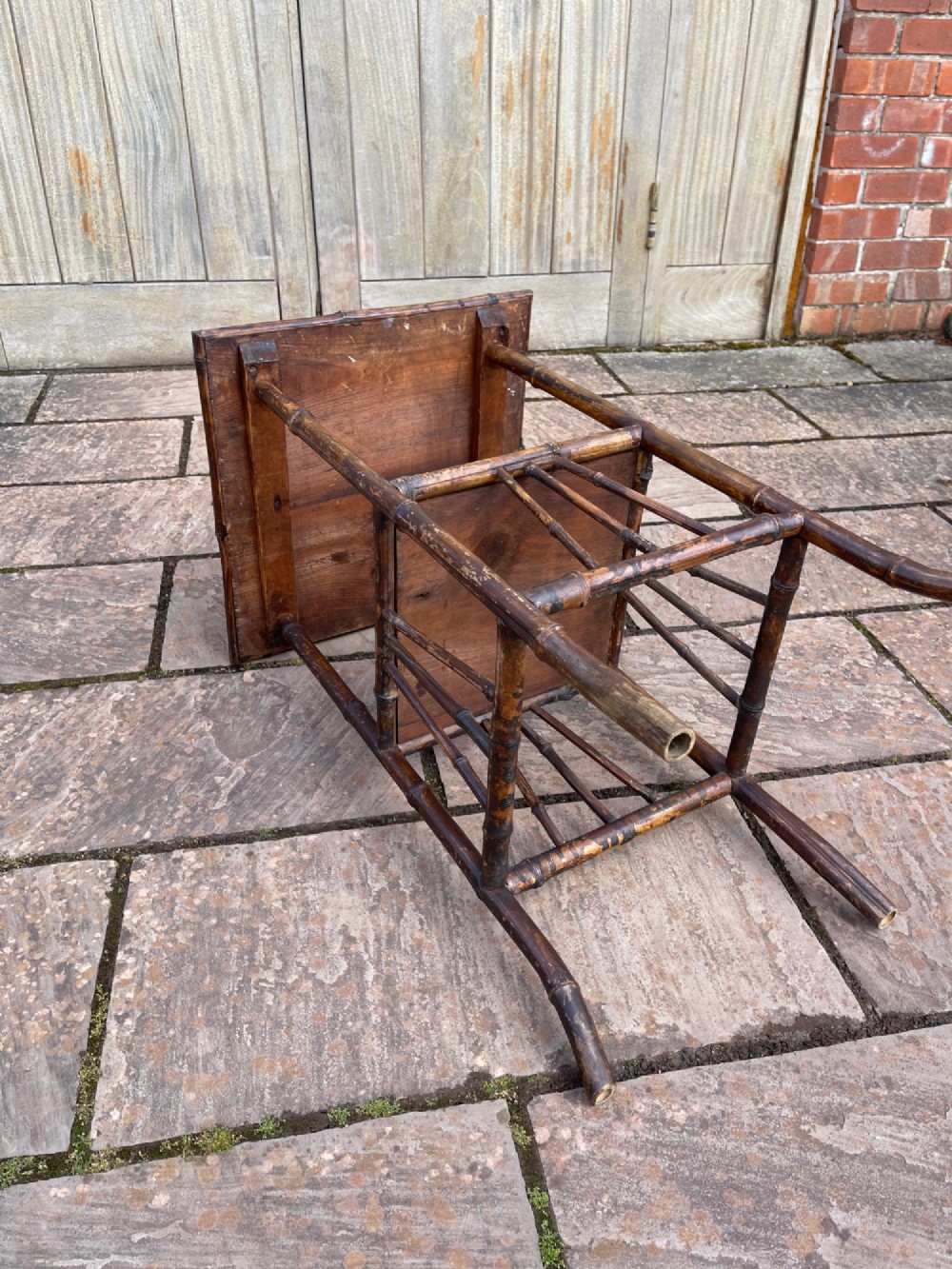A late Victorian two-tier side table constructed from a dark bamboo frame with woven cane surfaces on the square top and lower shelf. View III