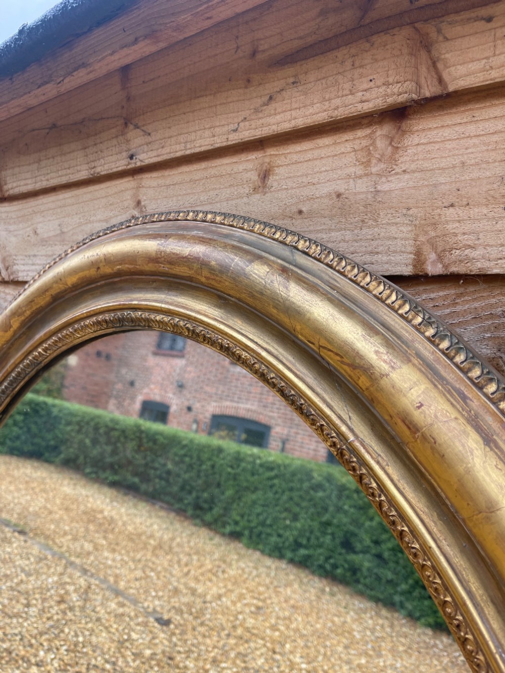 A large oval wall mirror featuring a gilded wood and gesso frame with beaded and moulded decorative borders. View II