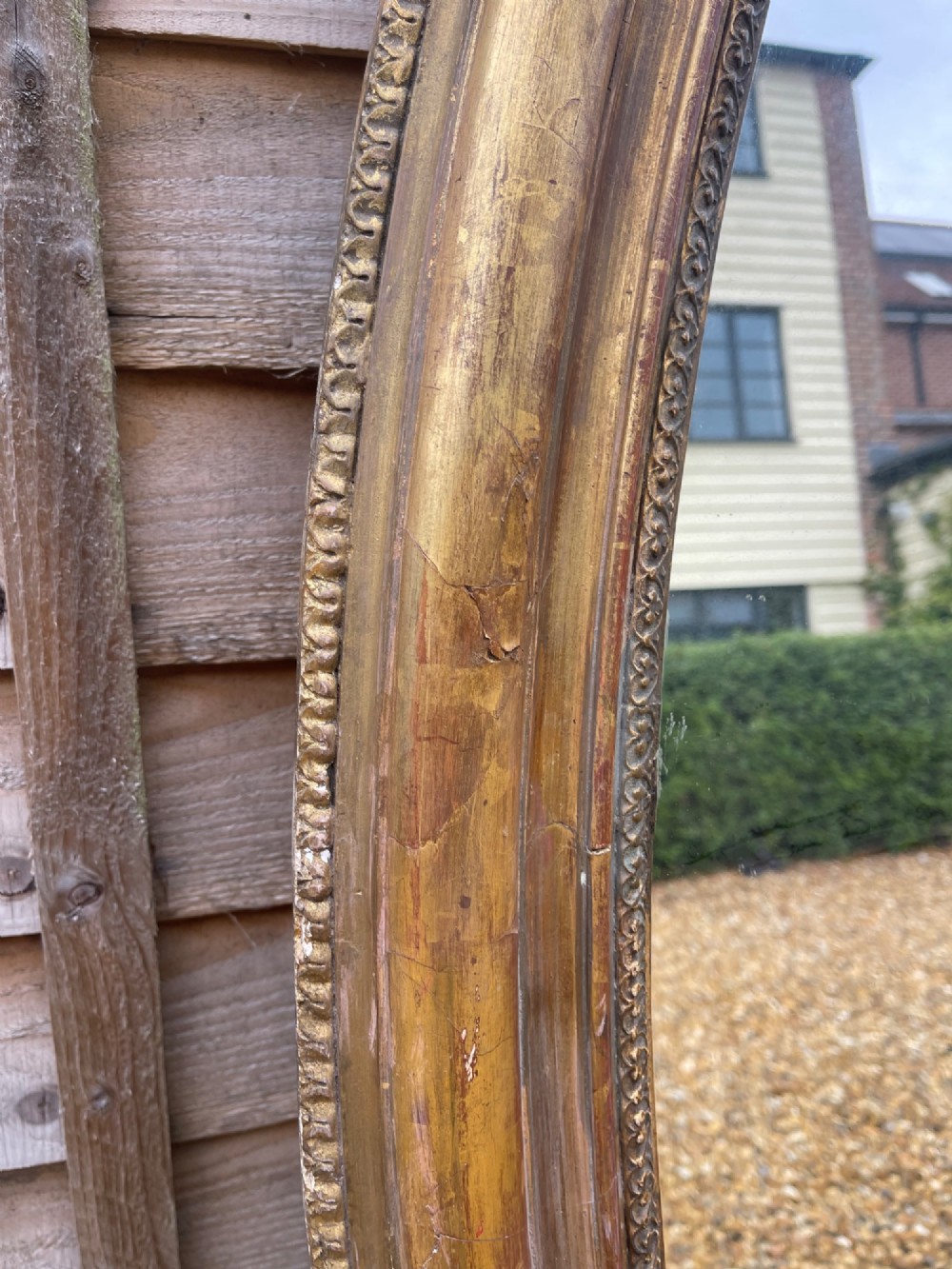 A large oval wall mirror featuring a gilded wood and gesso frame with beaded and moulded decorative borders. View IV