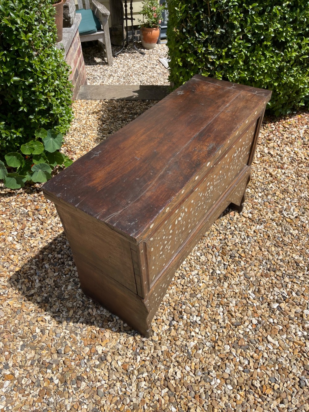 A dark walnut Syrian storage trunk decorated with detailed white mother-of-pearl floral and geometric inlay across the front panel and raised trestle base. View II
