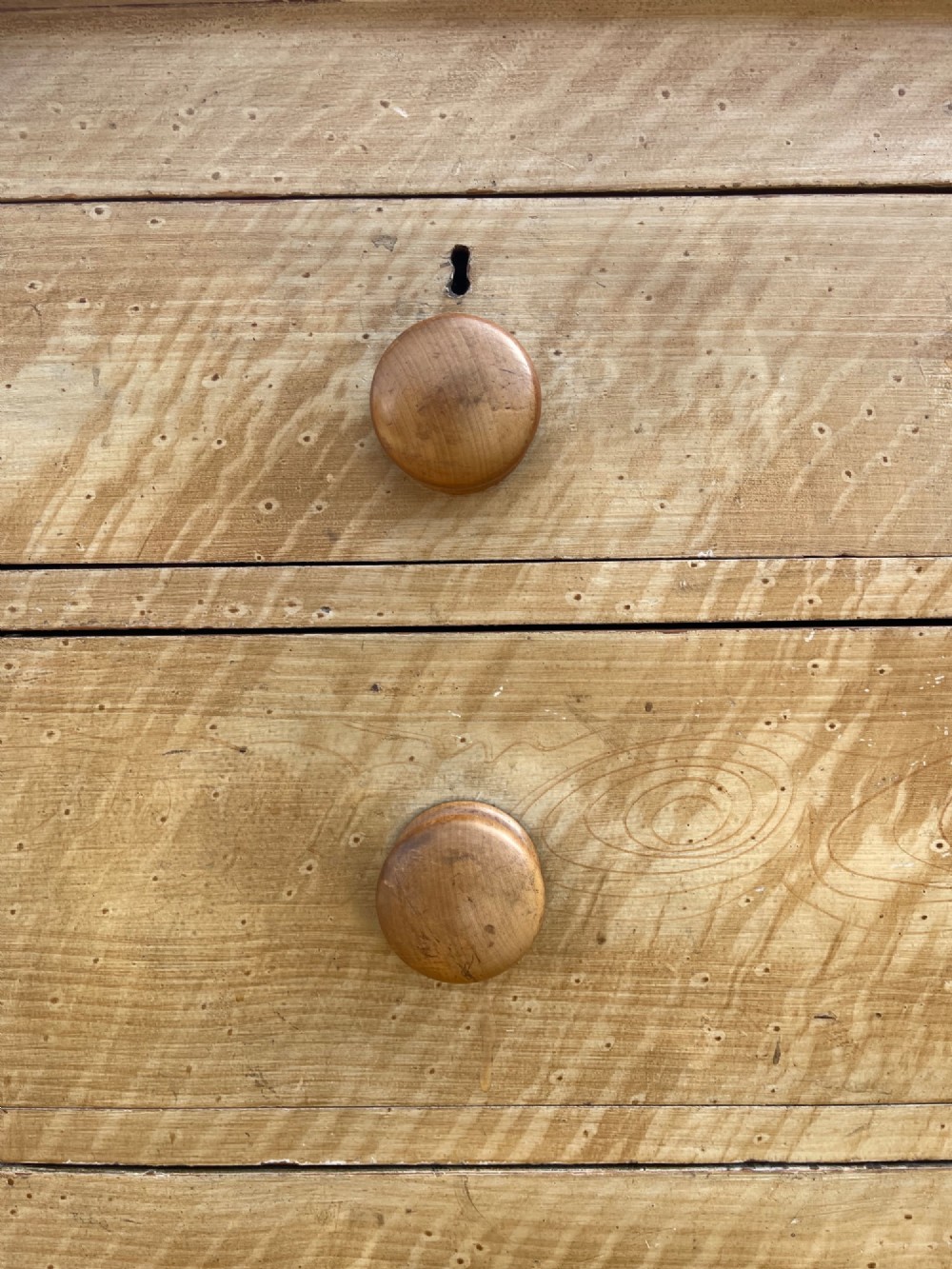 A Victorian pine chest of drawers with an original light brown faux-grain painted finish, featuring two short drawers over three long drawers with turned wooden handles and bun feet. View II