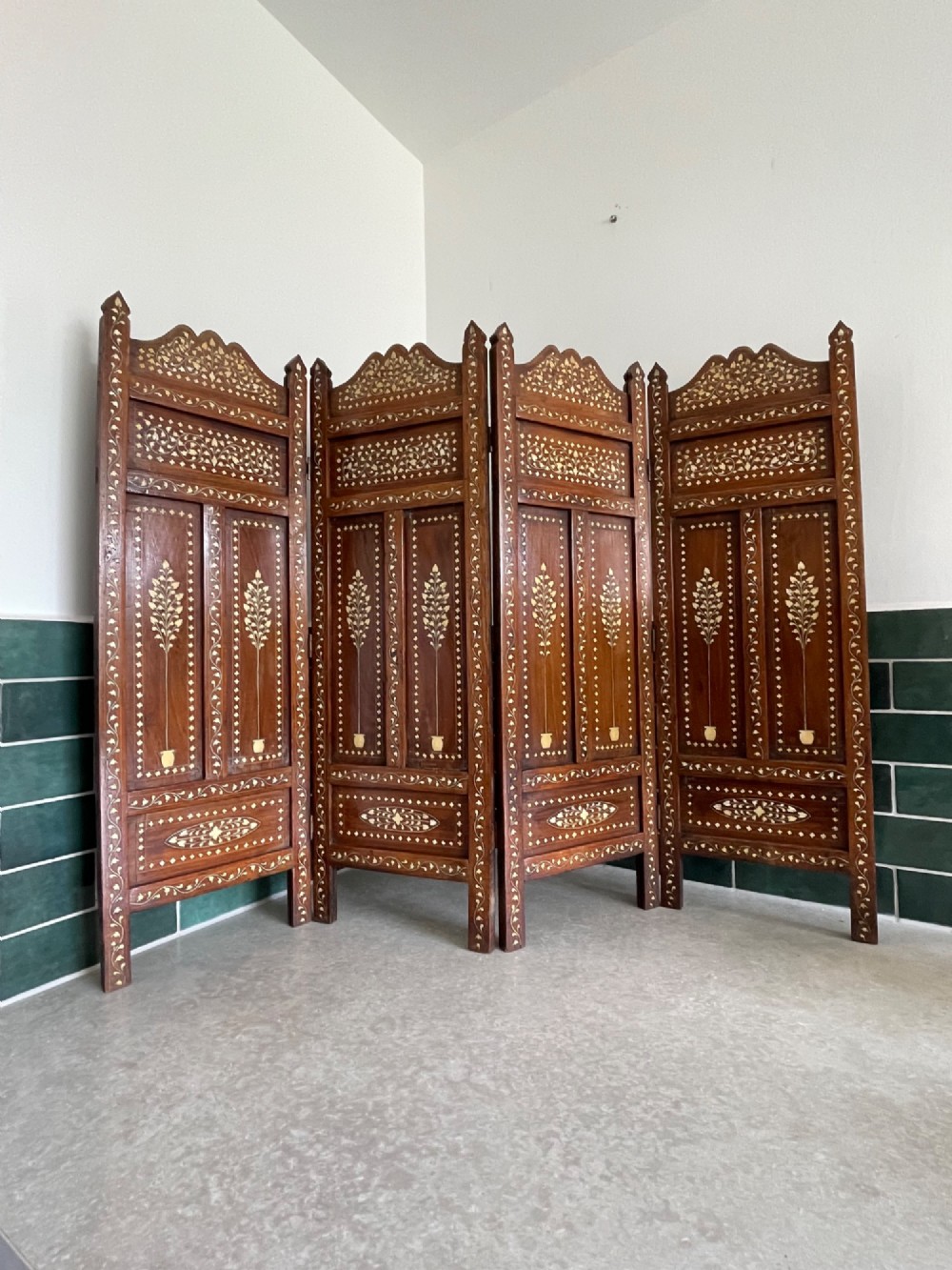 A four-panel Anglo-Indian miniature folding table screen constructed from dark brown wood with dense floral bone inlay decoration.