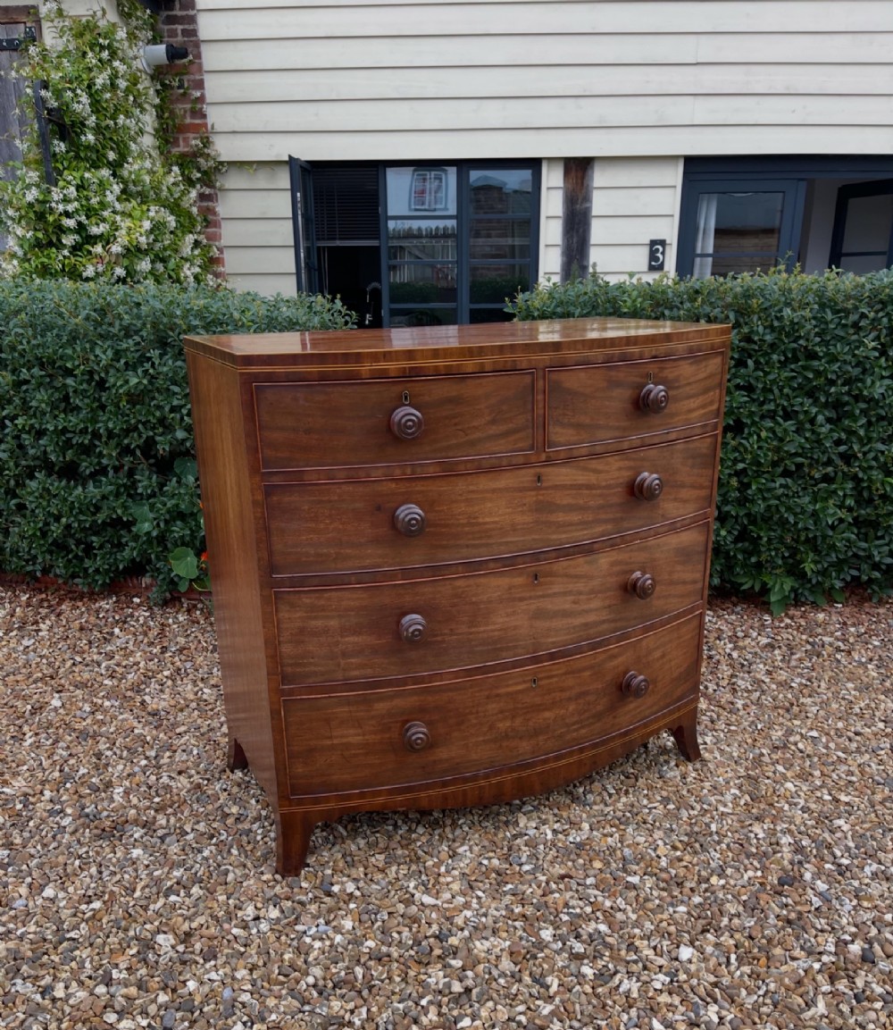 A Georgian mahogany bowfronted chest of drawers featuring two short over three long drawers with turned wooden knobs and splayed bracket feet.