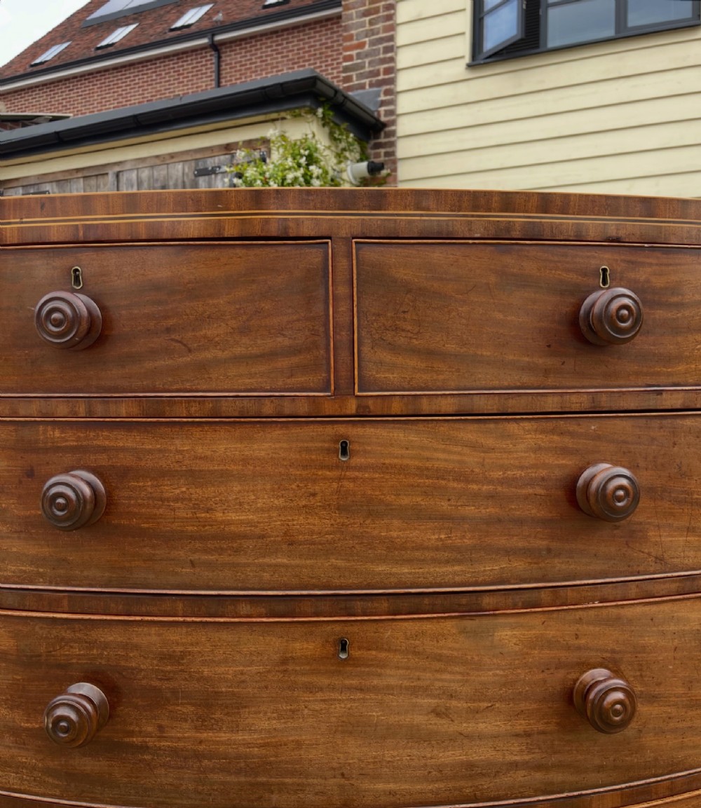 A Georgian mahogany bowfronted chest of drawers featuring two short over three long drawers with turned wooden knobs and splayed bracket feet. View II