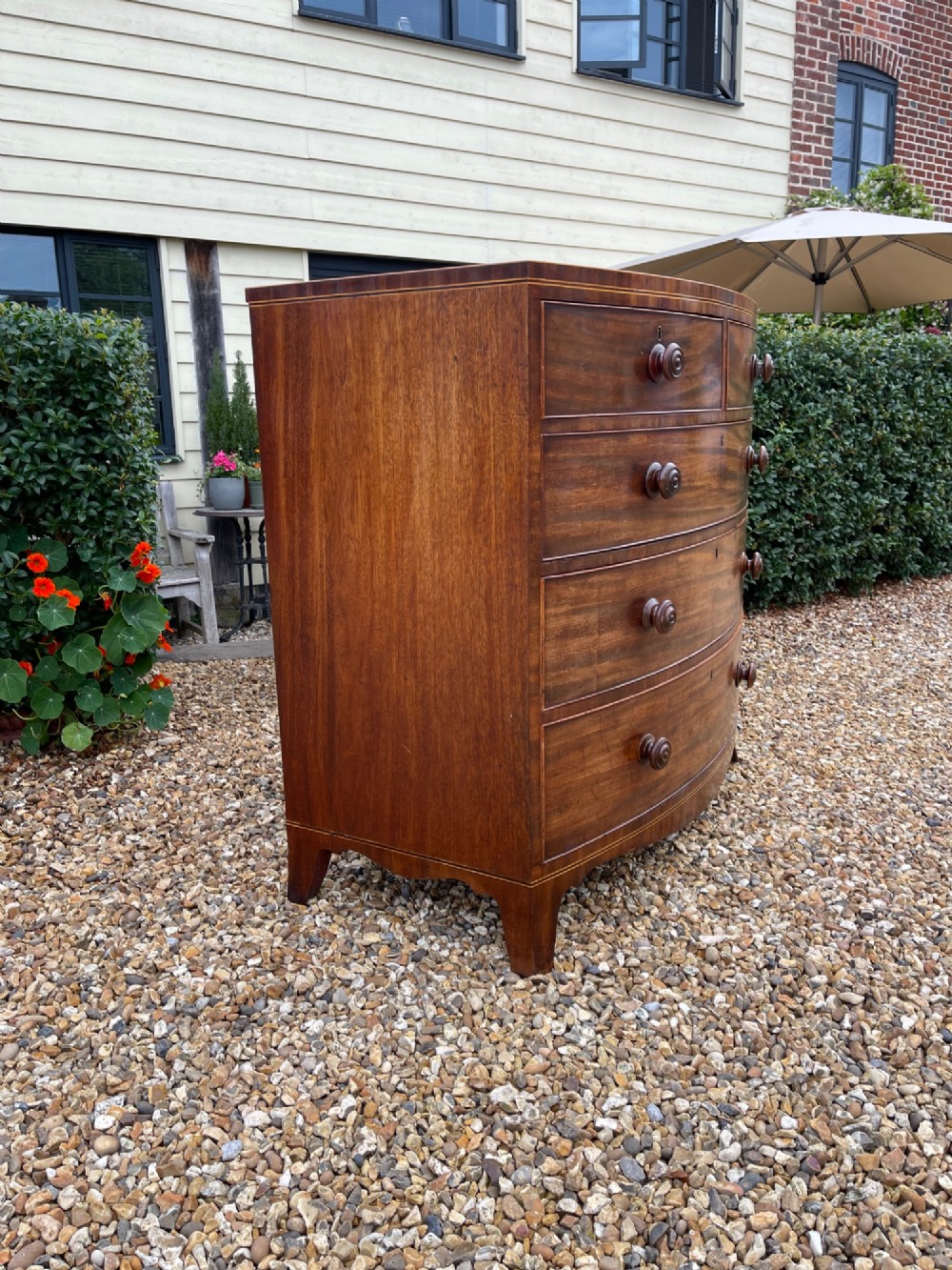 A Georgian mahogany bowfronted chest of drawers featuring two short over three long drawers with turned wooden knobs and splayed bracket feet. View IX