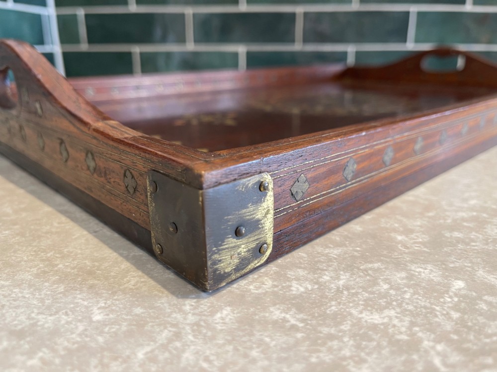 A rectangular dark hardwood serving tray featuring intricate floral and geometric brass inlay with cut-out side handles. View V