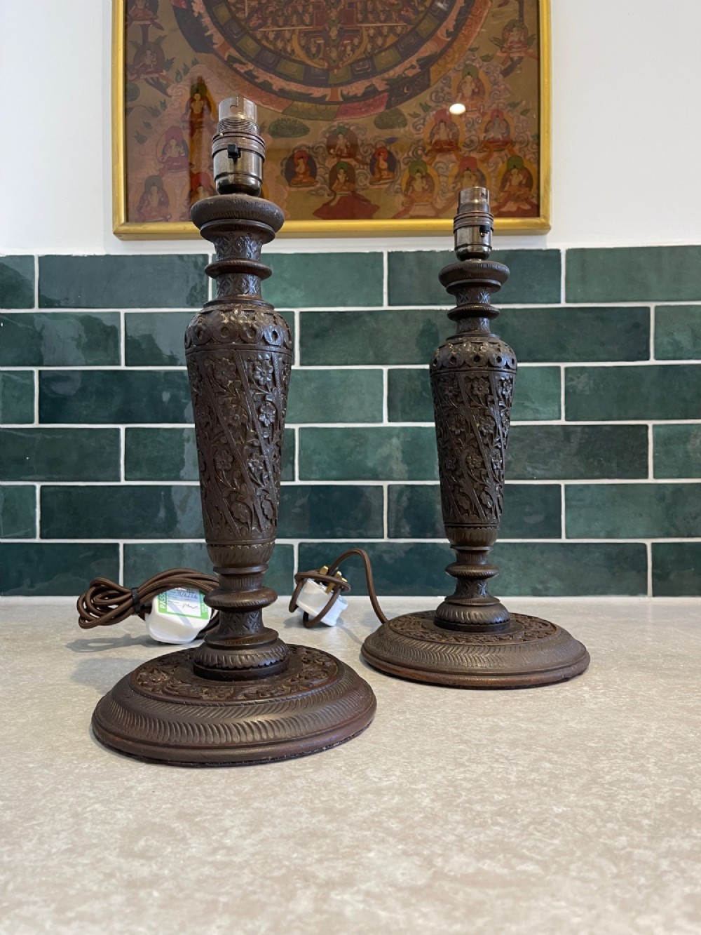 A pair of hand-carved dark brown walnut table lamp bases featuring turned baluster columns and detailed floral relief carving.