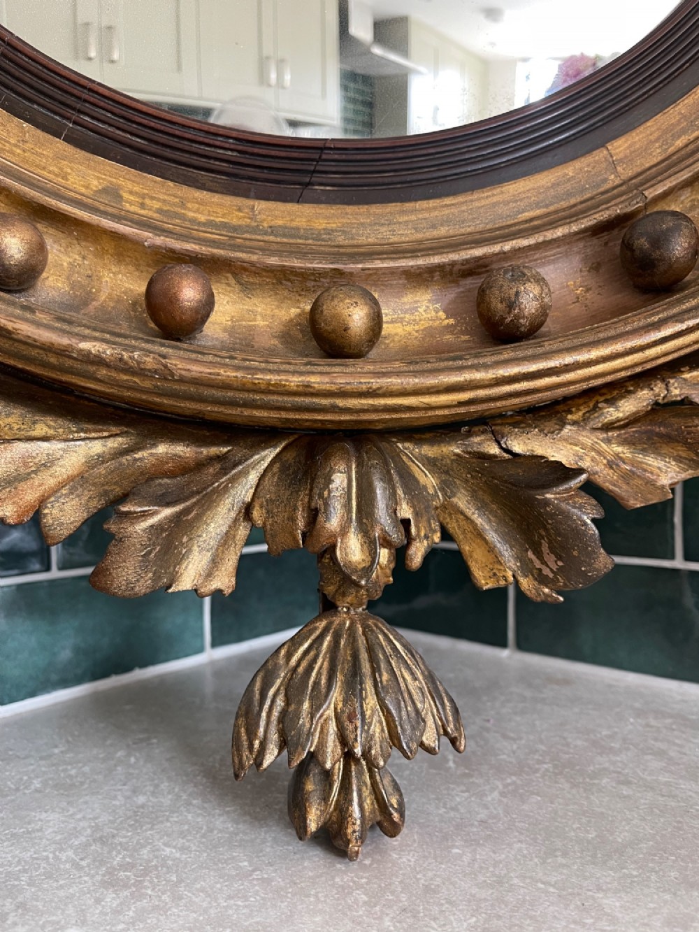 A circular Georgian giltwood convex wall mirror topped with a carved eagle cresting and featuring a frame decorated with ball spherules and an acanthus leaf apron. View VI
