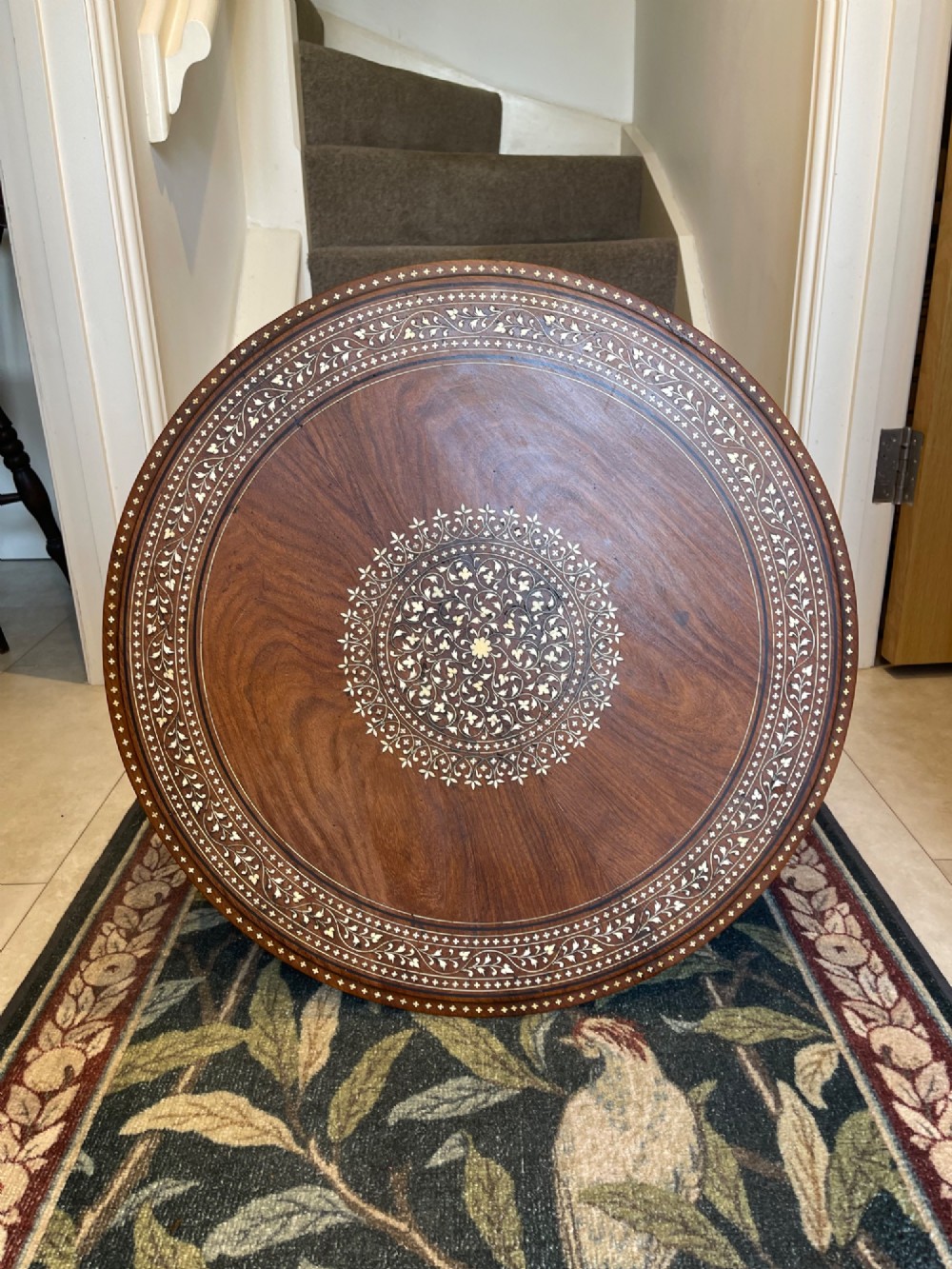A circular dark wood side table featuring elaborate floral bone inlay work and three carved elephant head legs. View II