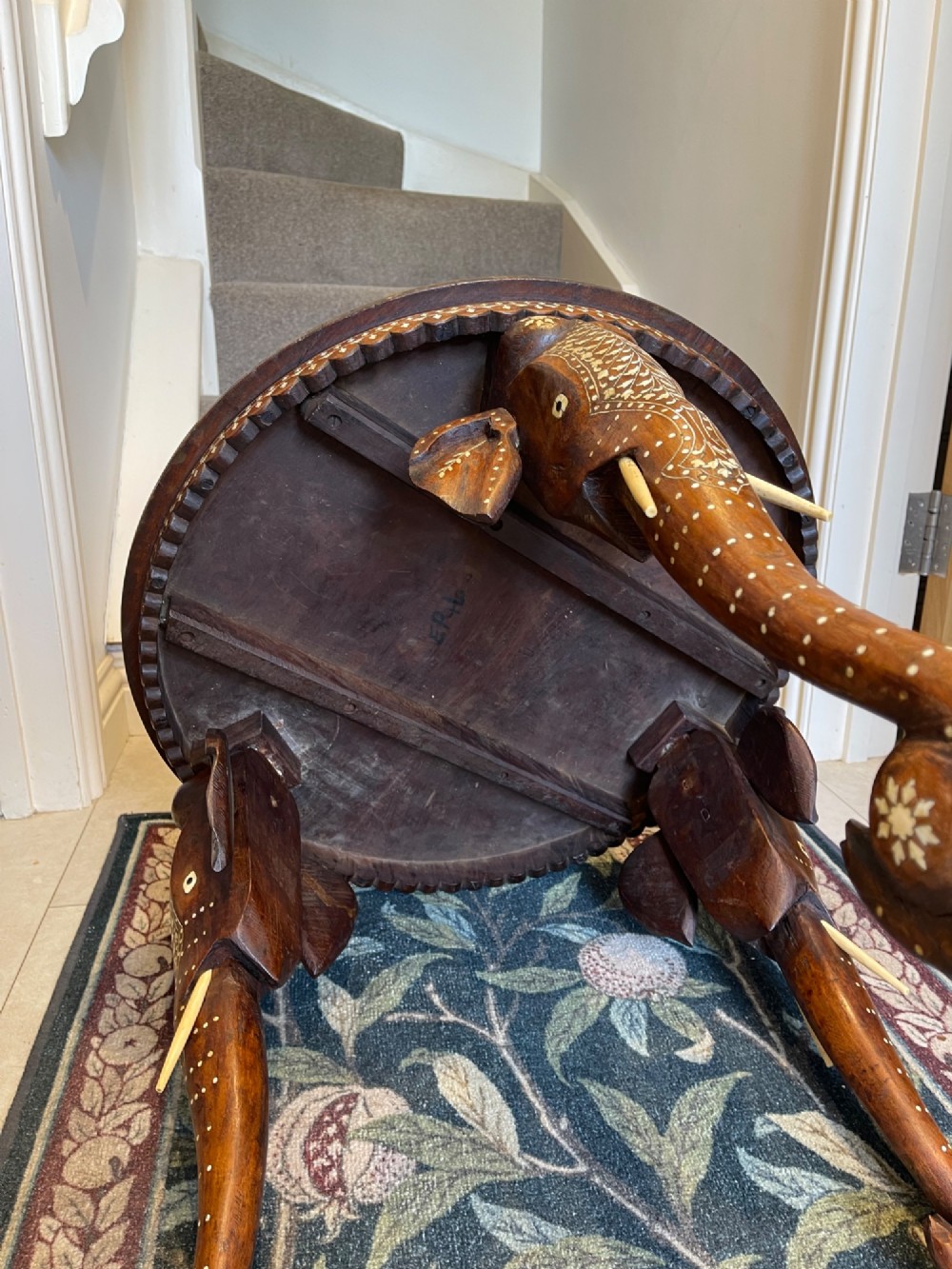 A circular dark wood side table featuring elaborate floral bone inlay work and three carved elephant head legs. View IV