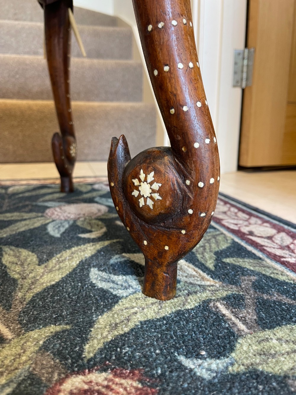 A circular dark wood side table featuring elaborate floral bone inlay work and three carved elephant head legs. View V