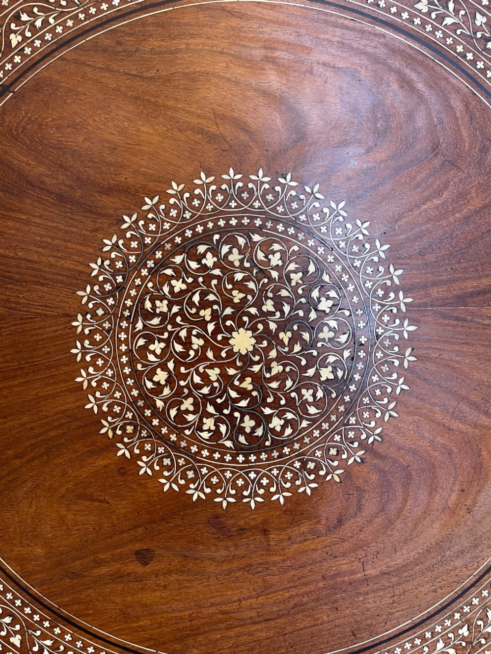 A circular dark wood side table featuring elaborate floral bone inlay work and three carved elephant head legs. View VI