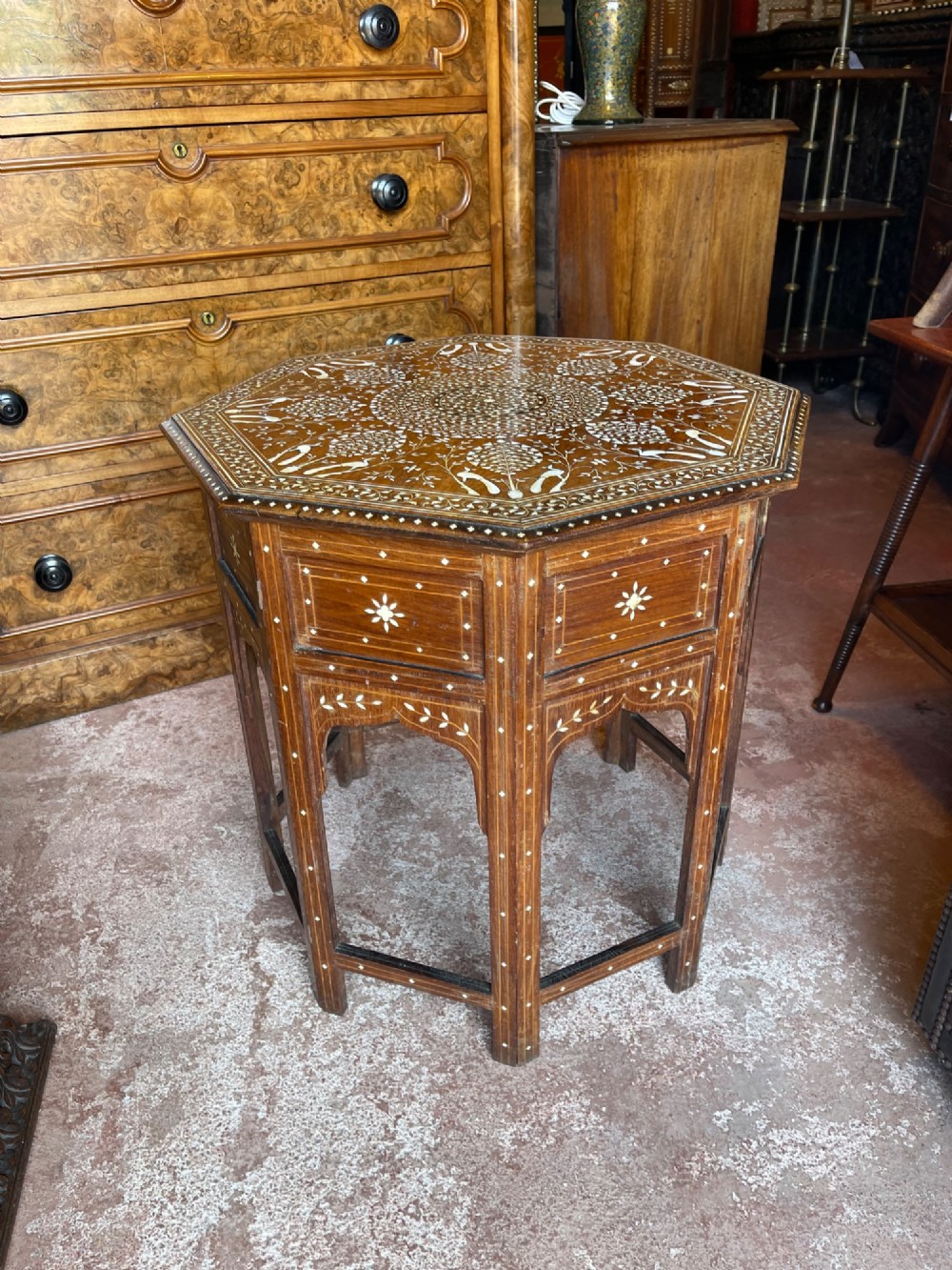 An octagonal Anglo-Indian dark wood side table decorated with dense bone inlay featuring floral patterns, geometric borders, and arched legs.