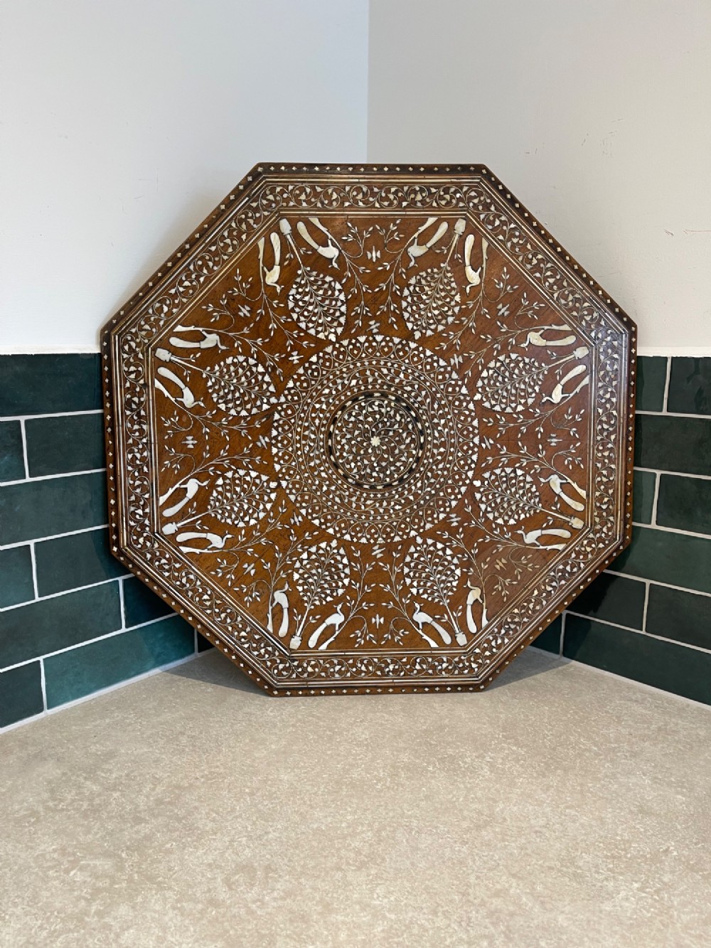 An octagonal Anglo-Indian dark wood side table decorated with dense bone inlay featuring floral patterns, geometric borders, and arched legs. View III
