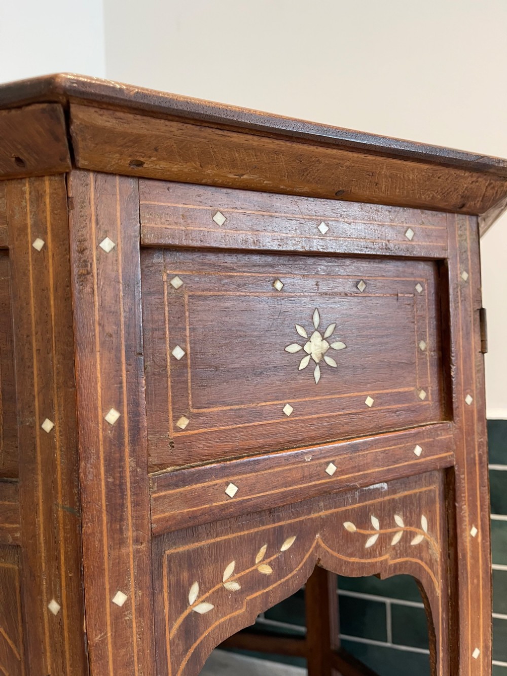 An octagonal Anglo-Indian dark wood side table decorated with dense bone inlay featuring floral patterns, geometric borders, and arched legs. View V