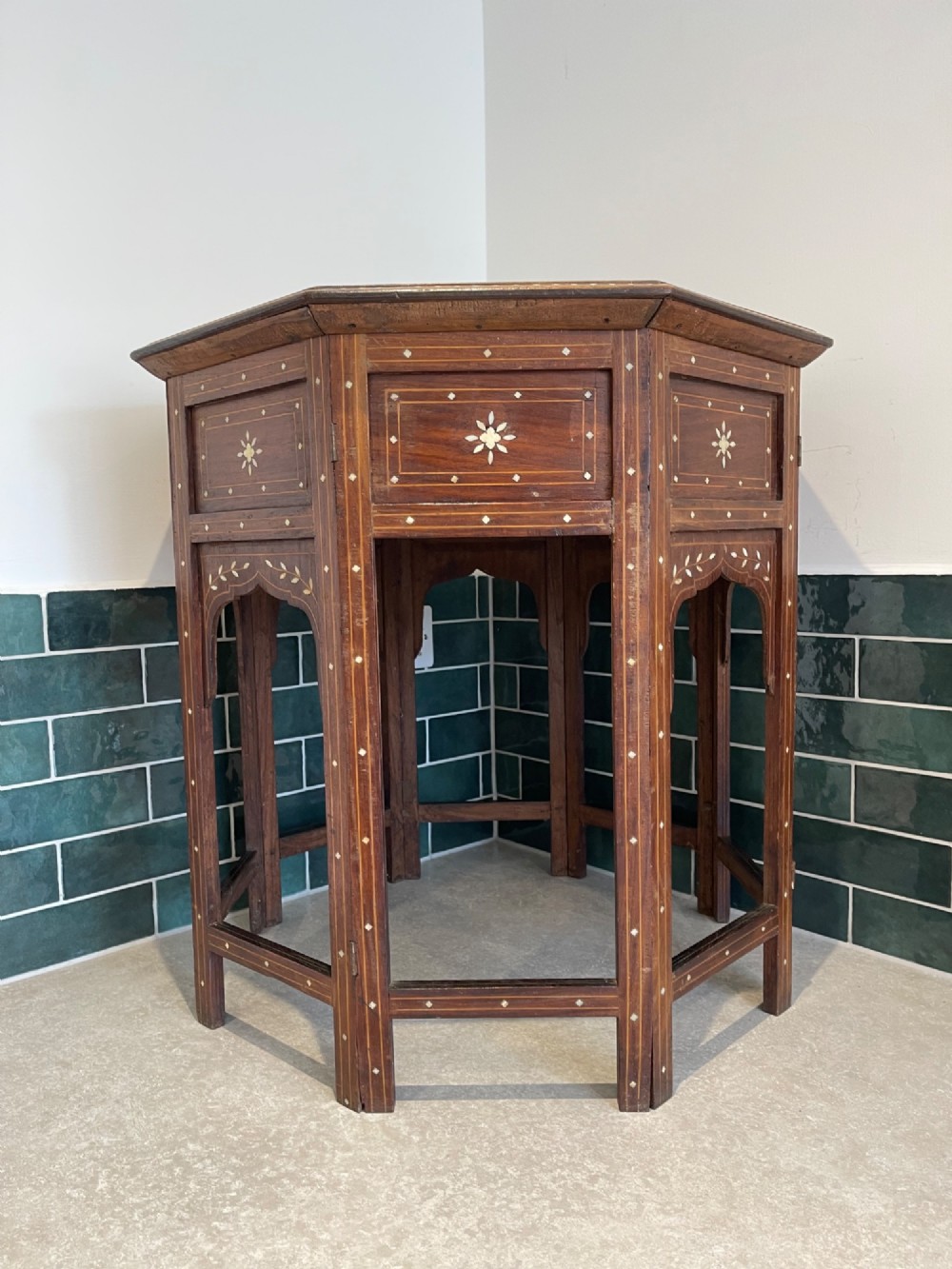 An octagonal Anglo-Indian dark wood side table decorated with dense bone inlay featuring floral patterns, geometric borders, and arched legs. View VIII