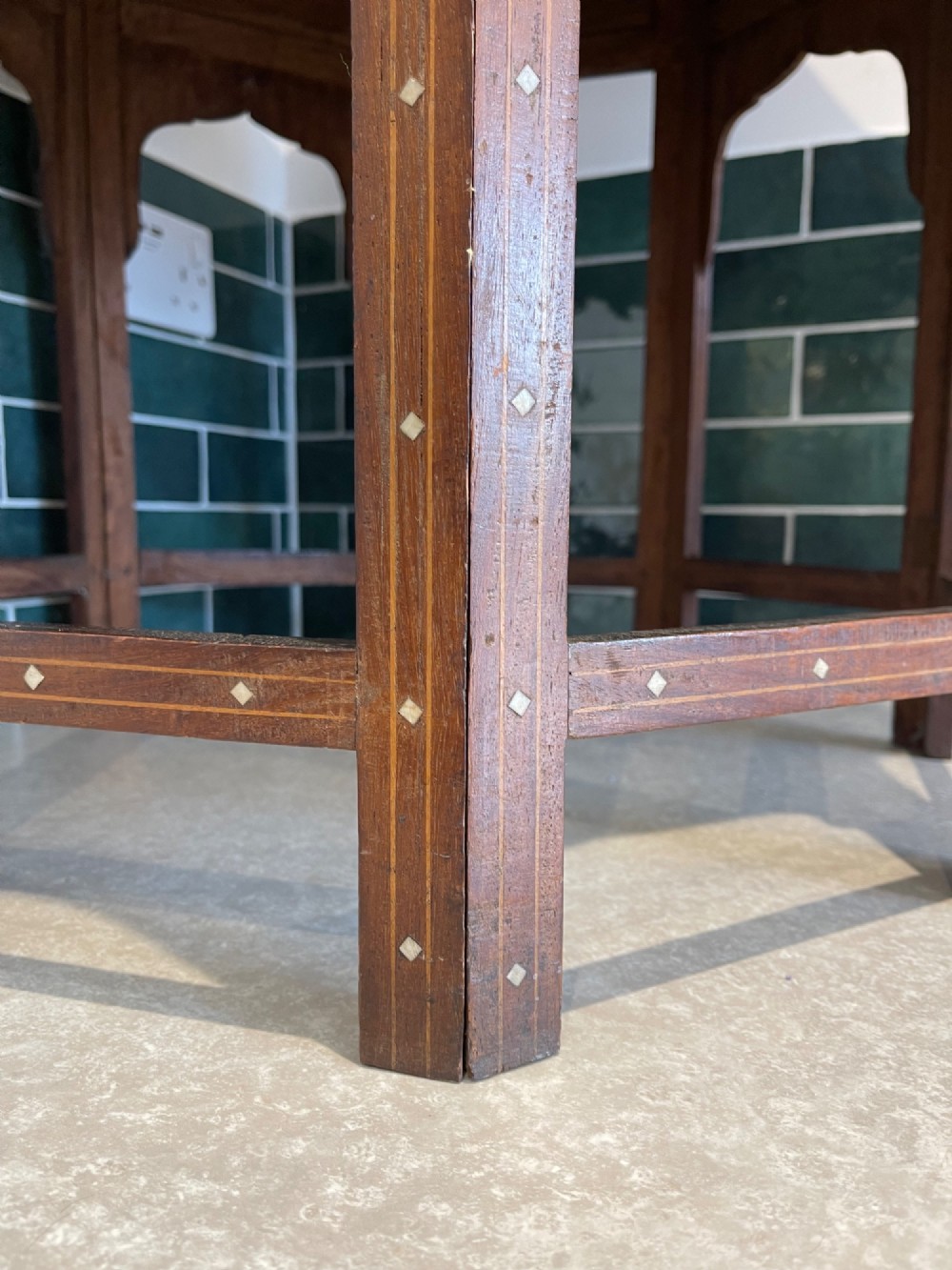 An octagonal Anglo-Indian dark wood side table decorated with dense bone inlay featuring floral patterns, geometric borders, and arched legs. View IX