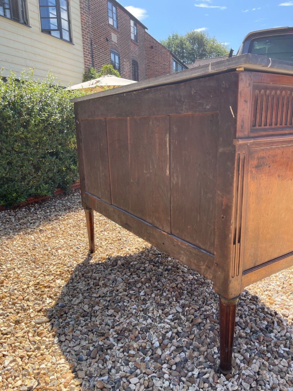 An 18th-century French cherrywood commode featuring a dark grey marble top, three frieze drawers above two long drawers, fluted sides, brass ring handles, and tapered legs. View VII