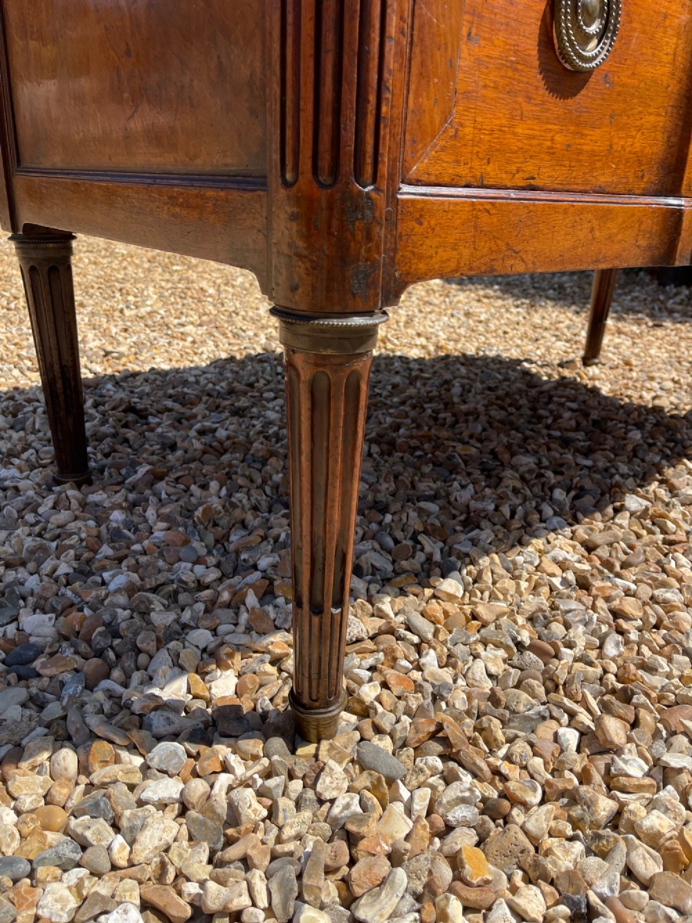 An 18th-century French cherrywood commode featuring a dark grey marble top, three frieze drawers above two long drawers, fluted sides, brass ring handles, and tapered legs. View IX
