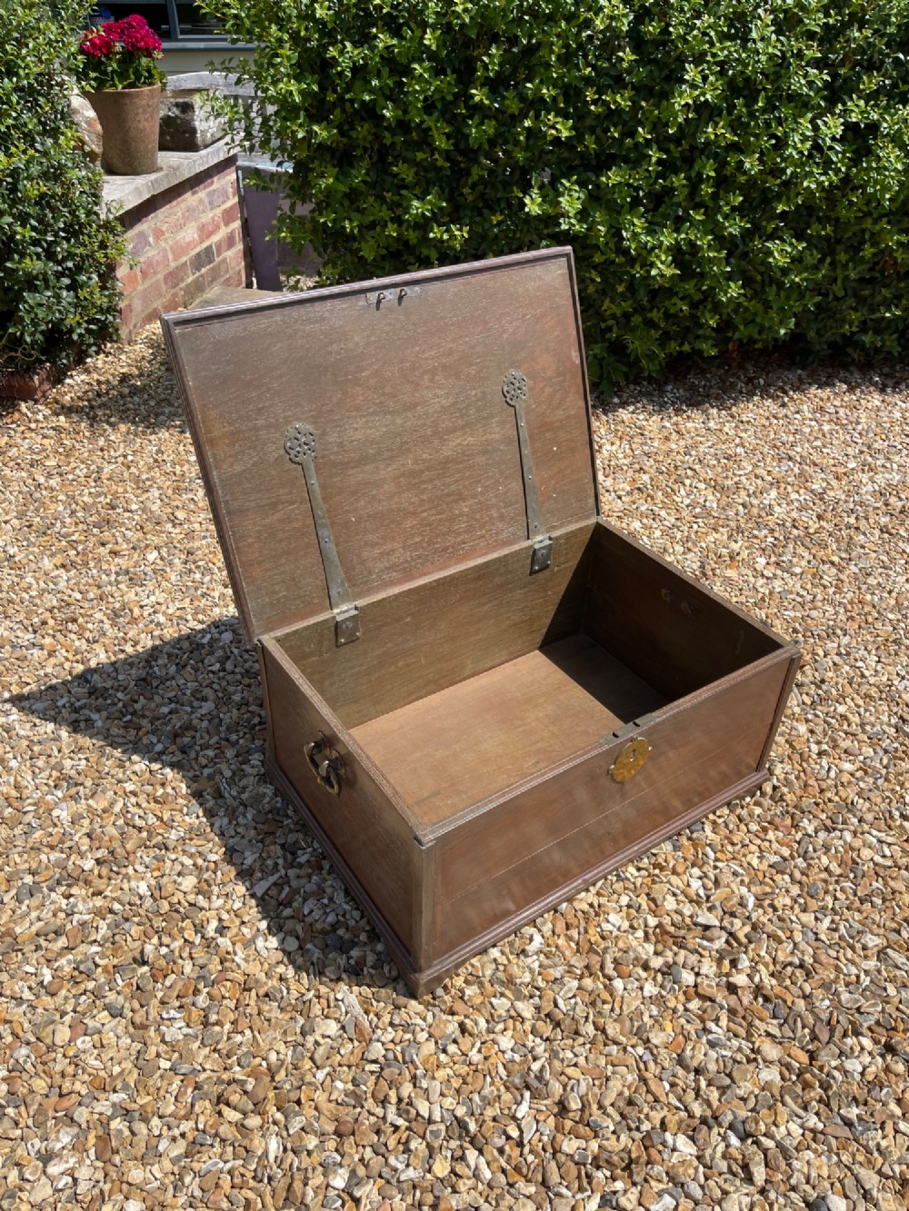 A late eighteenth-century rectangular warm brown teak trunk with a brass keyhole escutcheon, ribbed metal bosses on the lid, and metal side carrying handles. View IV