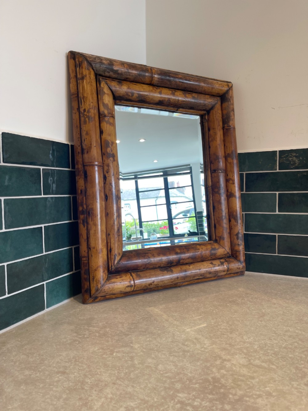 A rectangular wall mirror with a double-layered frame crafted from natural tortoiseshell-patterned bamboo poles.